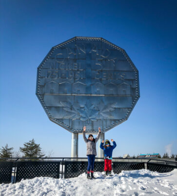 Two children in winter at the base of the Big Nickel in Sudbury